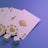 A set of playing cards displaying four aces is laid out on a surface. Alongside them, there are two poker chips with heart and diamond symbols, and three six-sided dice showing different numbers. The background is a smooth gradient of purple, creating a thematic gaming or casino atmosphere.